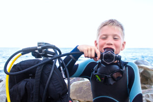 cheerful boy with blond hair breathes through a diving balloon